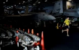 Un membre de l'équipage du porte-avion USS HArry S. Truman fait un jogging devant des chasseurs Super Hornet F-18, le 8 mai 2018