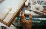L'artisan Cheung Shun-king grave des caractères chinois sur des tuiles de mah-jong dans son échoppe du quartier de Yau Tsim Mong, le 6 juillet 2022 à Hong Kong