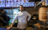 Arif Keles pose evant une broche de viande à kebab, le 19 avril 2024 à Berlin