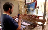 Un homme tisse un tapis traditionnel dans une échoppe du marché de Hilla, le 12 octobre 2017 en Irak