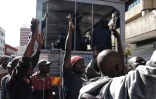 Des policiers anti-émeute sont stationnés devant la MDC, où des partisans de l'opposition dansent, sûrs de leur victoire, le 1er août 2018 à Harare