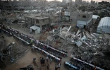 Une photo aérienne montre des Palestiniens rassemblés pour un repas de rupture du jeûne du ramadan, au milieu de la dévastation dans le camp de réfugiés de Nousseirat dans le centre de la bande de Gaza, le 14 mars 2025
