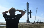 Une personne portant un T-shirt de l'entreprise SpaceX regarde la fusée Starship sur son pas de tir, le 16 novembre 2023 à Boba Chica (Etats-Unis)