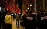 Des badauds passent sur les Champs Elysées à Paris alors que des policiers patrouillent pour faire respecter le port du masque, le 31 décembre 2021