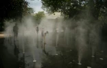Des enfants se rafraîchissent dans une fontaine à brume dans le centre de Paris le 13 août 2025, en pleine canicule
