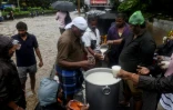 Des bénévoles distribuent du riz au lait à des habitants au bord d'une route inondée après le passage du cyclone Nivar, à Pondichéry en Inde le 26 novembre 2020