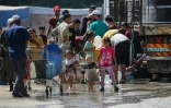 Des Palestiniens se rassemblent pour remplir leurs conteneurs d'eau à Nousseirat, dans le centre de la bande de Gaza, le 24 mai 2025
