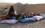 Une femme afghane et des enfants dorment sur des couvertures après le séisme dans le village de Sarbuland du district de Zendeh Jan dans la province d'Hérat, le 7 octobre 2023