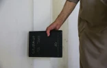 Mustafa Khaled Alwan tient un livre près de l'emplacement du faux mur qui dissimulait sa bibliothèque, chez lui à Homs, en Syrie, le 19 septembre 2026