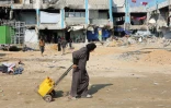 Une Palestinienne tire un chariot chargé de bidons d'eau, à Jabalia, dans le nord de la bande de Gaza, le 4 février 2025
