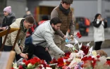 Des hommes déposent des fleurs au mémorial pour les victimes de l'attentat du Crocus City Hall, le 29 mars 2024 à Krasnogorsk, dans la banlieue de Moscou