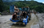 Des sauveteurs transportent des habitants bloqués à l’aide d’un bulldozer après des crues soudaines dans la région de Devighat, dans le district de Nuwakot au Népal, le 27 août 2026