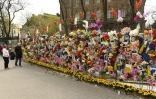 Des passants s'arrêtent devant un mur de fleurs artificielles et de photos de victimes tuées depuis le début de l'invasion russe, le 24 avril 2022 à Lviv, plus grand ville de l'ouest ukrainien