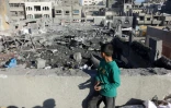 Un enfant palestinien debout sur un toit regarde la destruction après une frappe israélienne qui a touché une école transformée en abri pour déplacés dans la ville de Gaza, le 13 avril 2025