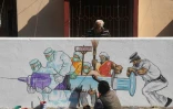 Des artistes terminent une peinture murale représentant des soignants portant le vaccin contre le virus à Kolkata le 2 janvier 2021