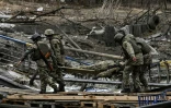Des soldats ukrainiens transportent le corps d'un camarade Ă Irpin (nord-ouest de Kiev) le 13 mars 2022