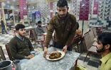 Un serveur apporte une assiette de kebabs à des clients du restaurant Tory Kebab House à Namak Mandi, dans le coeur gastronomique de Peshawar, le 13 décembre 2018