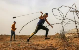 Un Palestinien utilise un lance-pierres pour jeter des pierres sur les forces de police israéliennes, le 9 mai 2021 dans le sud de la bande de Gaza