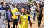 Un jeune Palestinien montre des paquets de farine qu'il a reçus dans la région de Rafah, dans le sud de la bande de Gaza, le 28 juillet 2025