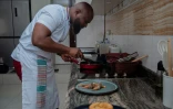 Le chef congolais Archi Dimosi fait frire des aliments dans une poêle pendant qu'il prépare un plat dans sa cuisine à Kinshasa, le 17 mai 2026 en RDC