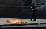 Un corps gît sous un drap à Toronto le 23 avril 2018 après qu'une camionnette a fauché une dizaine de piétons