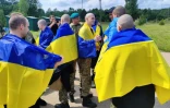 Photo prise et diffusée par le service de presse présidentiel ukrainien, le 9 juin 2025, de prisonniers de guerre ukrainiens enveloppés de drapeaux nationaux après un échange dans un lieu non divulgué