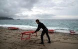 Un plagiste installe des chaises longues sur une plage à Noli, près de Gênes en Italie, le 16 mai 2021 pour le début de la saison