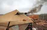 Une fumée noire s'échappe de la tente du réfugié Oum Raed, le 16 décembre 2021 au camp de déplacés de Kfar Arouk, dans le nord-ouest de la Syrie