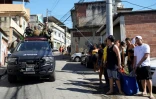 Un véhicule des forces de l'ordre passe à côté d'habitants portant un cadavre lors d'une opération policière dans la favela Complexo do Alemao à Rio de Janeiro, le 21 juillet 2022