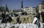 Des employés municipaux remplissent des sacs de sable pour les disposer autour de momuments qu'ils espèrent protéger des bombardements russes, le 26 mars 2022 à Kharkiv (est de l'Ukraine)