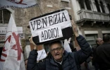 Un homme porte une valise surlaquelle on peut lire "Venise adieu" pendant une manifestation contre le tourisme de masse dans la cité des Doges, le 12 novembre 2016 