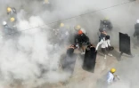 Des manifestants pris dans la fumée de gaz lacrymogènes envoyés par les forces de l'ordre et de gaz d'extincteurs utilisé par certains manifestants, à Rangoun, le 6 mars 2021