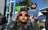 Des enfants du sud-est asiatique scrutent le ciel munis de lunettes spéciales pour observer l'éclipse