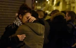 Des gens se rassurent mutuellement lors d'un rassemblement devant le Carillon, à Paris, le 15 novembre 2015