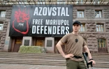 Le soldat ukrainien Vladyslav Jaïvoronok du régiment Azov, amputé d'une jambe, devant une affiche géante "Libérez les défenseurs de Marioupol", le 16 août 2022 à Kiev