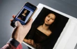 Un homme prend une photo d'un portrait de Marie-Madeleine attribué au peintre et architecte italien de la Renaissance Raphaël, le 21 octobre 2023 à Paris