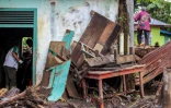 Des personnes nettoient une maison endommagée par la boue et les troncs d'arbres emportés par des crues soudaines dans le village de Rambatan, en Indonésie, le 14 mai 2024
