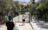 Un touriste pose devant l'entrée de l'Acropole fermée pour cause de canicule à Athènes, le 14 juillet 2023