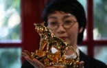 Une femme pose avec une figurine de tigre plaquée or à Hanoï au Vietnam le 19 janvier 2022