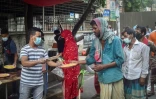 Un bénévole de l'association Mehmankhana distribue des repas à des personnes sans ressources affectées par la crise sanitaire, le 26 juillet 2021 à Dacca