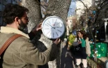 L'artiste de rue Hikmeti Tabiyeci installe sur un arbre une "horloge politique", l'une de ses créations, le 25 décembre 2023 à Ankara, en Turquie
