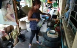 Florivic Baldoza, prépare des repas qu'elle vendra aux ouvriers qui réparent une digue voisine, dans l'école qui sert de logement temporaire à sa famille, dans le village de San Francisco à Guinobatan, aux Philippines, le 5 octobre 2021