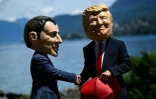 Des manifestants affublés de grosses têtes caricaturant le président français Emmanuel Macron et le président américain Donald Trump, posent lors d'un événement organisé par l'ONG Oxfam, à Publier, près d'Evian, dans l'est de la France, le 14 juin 2026