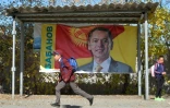 Un enfant court devant une affiche de campagne du candidat à l'élection présidentielle Omourbek Babanov, à Prokhladnoye au Kirghizstan, le 12 octobre 2017