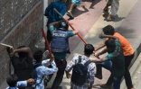 Des manifestants frappent un policier à coups de bâton à Dacca, le 18 juillet 2024