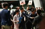 La cheffe de l'exécutif hongkongais Carrie Lam (c) quitte le Parlement local après avoir été chahutée par des parlementaires, le 16 octobre 2019