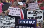 Donald Trump brandit deux panneaux "Les femmes avec Trump" et "Les noirs avec Trump", le 12 octobre 2016 à Lakeland en Floride