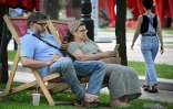 Des personnes assises sur des transats utilisent leurs smartphones à Moscou, le 30 juillet 2025