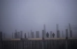Des ouvriers du bâtiment travaillent, environnés par un brouillard blanchâtre provoqué par la pollution,à Shtime, au Kosovo, le 16 janvier 2020.