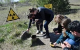 Des touristes mesurent le degré de radioactivité dans la "forêt rouge" devant le réacteur Numéro 4 de Tchernobyl, le 23 avril 2018